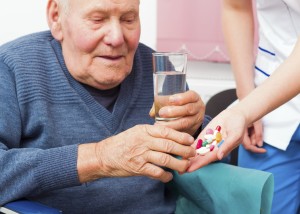 Senile elderly man taking daily medicine at the nursing home.