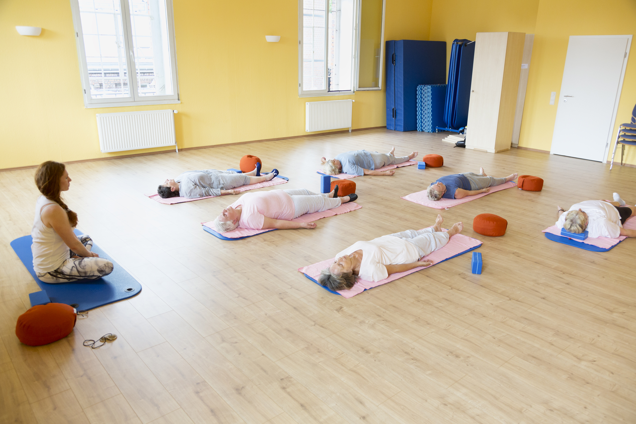 Yoga class with senior women lying down on exercise mat, relaxation exercise